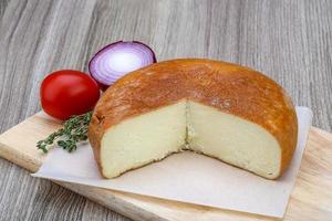 Suluguni cheese on wooden board and wooden background photo