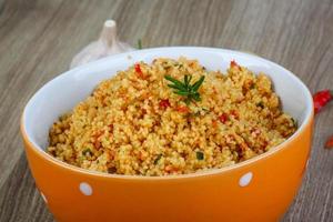 Couscous in a bowl on wooden background photo