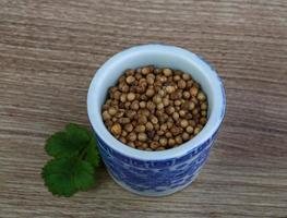 Coriander seeds in a bowl on wooden background photo