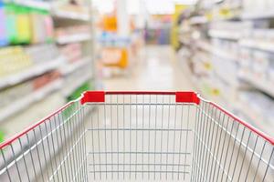 Empty shopping cart with abstract blur supermarket discount store aisle and product shelves interior defocused background photo