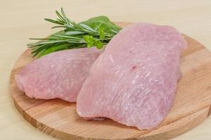 Turkey steak on wooden board and wooden background photo