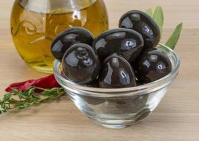 Black olives in a bowl on wooden background photo