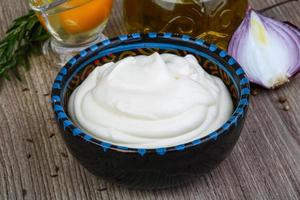 Mayonnaise sauce in a bowl on wooden background photo