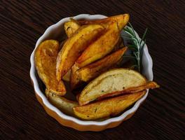 Roasted potato in a bowl on wooden background photo