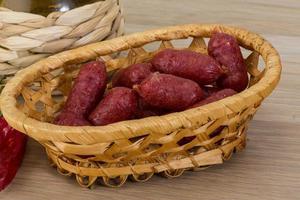 Mini salami in a basket on wooden background photo