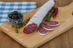 Fuet sausage on wooden board and wooden background photo