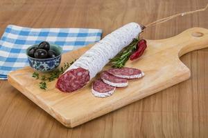 Fuet sausage on wooden board and wooden background photo