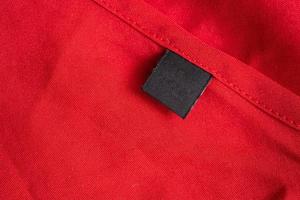 Blank black laundry care clothing label on red color fabric texture photo