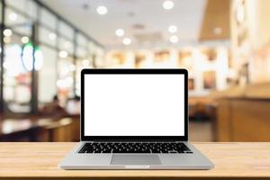 Blank screen laptop computer on wood table top with blur cafe restaurant with abstract bokeh light defocused background photo