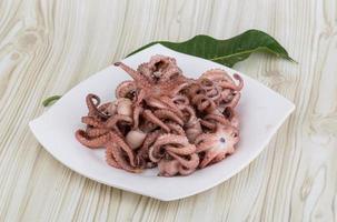 Boiled octopus on the plate and wooden background photo