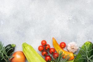 Set of different seasonal vegetables on a gray concrete background. Tomato zucchini onion garlic rosemary pepper spices. Frame copy space photo