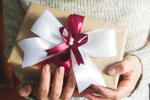 Gift or present box with a big bow in the hands of a woman in a sweater. composition for Christmas birthday, mother day or wedding. photo