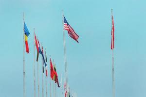 National flags of various countries flying on a blue sky. photo