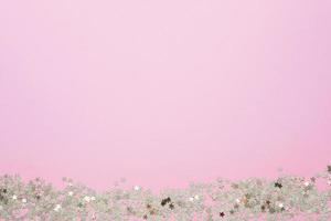 Confetti of gold stars glisten on a pink background. Festive holiday pastel backdrop. photo