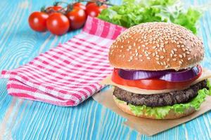 Homemade cheeseburger on blue wooden surface. photo