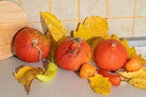 Seasonal harvest of pumpkins and vegetables, ingredients for preparing a dish, advertising and autumn concept - close-up of pumpkins and leaves on the table at home photo