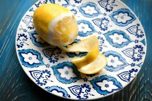 Yellow fresh lemon on the plate with blue pattern on wooden background photo