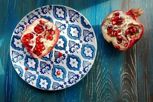 Garnet on plate with blue and white pattern on wooden background photo