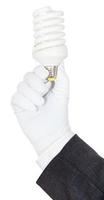 hand in business suit and glove holds CFL lamp photo