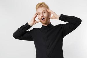 Excited surprised shock young man isolated on gray background. Happy Redhead guy with red beard in black stylish shirt. Success and pass exam concept. Copy space. Close up of Face expression. photo