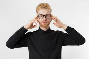 Young man in thinking process. Close up redheaded guy with red beard in black shirt, glasses focus on creating startup idea isolated on gray background. Intellect mind and brain power. Mental health. photo