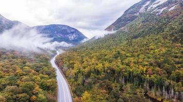 camino ventoso que atraviesa el bosque entre montañas en otoño foto