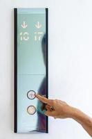 Asian old woman hand points to the button of elevator. photo