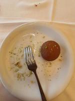 uno de los postres de pavo, gulab jamun, que se sirve hasta en dos piezas en un plato blanco. foto