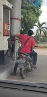 West Java in April 2019. A motorcyclist is buying petrol fraudulently. He bought by using a gallon that is placed on the front of the motorcycle. photo