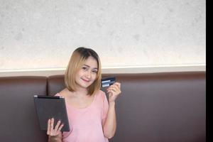 A woman holding a tablet and credit card using shopping online and making order on the internet at home photo