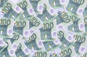 Background pattern of a set of green monetary denominations of 100 euros. A lot of money forms an infinite heap photo