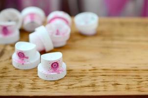 The soiled pink nozzles from the paint sprayer lies on a wooden plank on a background of a many dirty spray cans photo