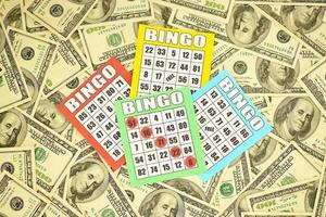 Many bingo boards or playing cards for winning chips and big amount of dollar bills. Classic american or canadian five to five bingo cards on money photo