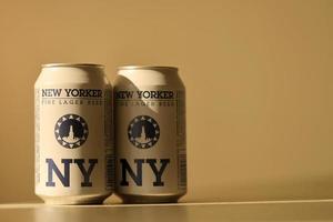 TERNOPIL, UKRAINE - JULY 18, 2022 Two cans of New Yorker fine lager beer with original logo and design on brown retro background photo