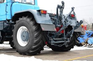 Wheels of back view of new tractor in snowy weather. Agricultural vehicle back view photo