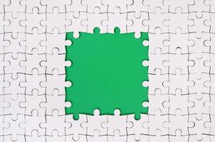 Framing in the form of a rectangle, made of a white jigsaw puzzle around the green space photo