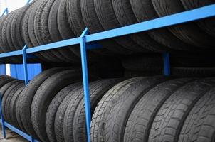 Rack with variety of car tires in automobile store. Many black tires. Tire stack background. Selective focus photo