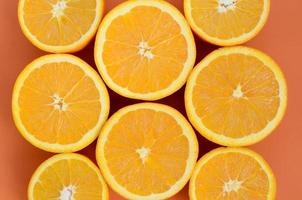 Top view of a several orange fruit slices on bright background in orange color. A saturated citrus texture image photo