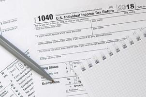 The pen and notebook is lies on the tax form 1040 U.S. Individual Income Tax Return. The time to pay taxes photo