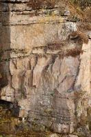 Light coarse natural rock stone background. Mining cliff rough front surface. Big limestone stack backdrop. Heavy grunge damaged granite block texture photo