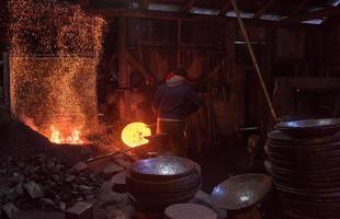 trabajadores del herrero que usan el martillo mecánico en el taller foto