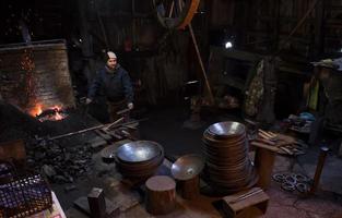 young traditional Blacksmith working with open fire photo