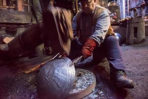 trabajadores del herrero que usan el martillo mecánico en el taller foto