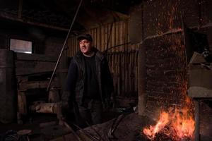 joven herrero tradicional trabajando con fuego abierto