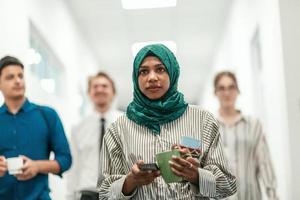 Multi-ethnic startup business team walking through the hallway of the building while coming back from a coffee break photo