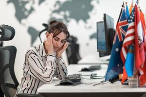 hermosa mujer joven sorprendida y molesta mirando su computadora portátil. mujer agente operadora triste que trabaja desde casa en un centro de llamadas foto