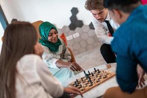 Multiethnic group of business people playing chess while having a break in relaxation area at modern startup office photo