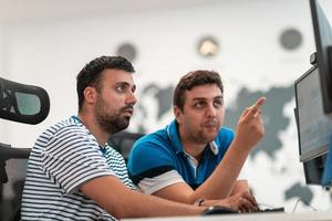 grupo de hombres de negocios casuales que trabajan en una computadora de escritorio en el moderno interior de la oficina de inicio de planta abierta. enfoque selectivo foto