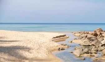 Sea, sand beach with rocks and blue sky. photo