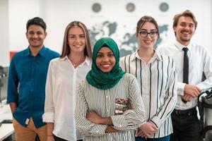 retrato de un joven equipo de negocios multiétnico emocionado de desarrolladores de software de pie y mirando la cámara en la oficina de inicio moderna foto